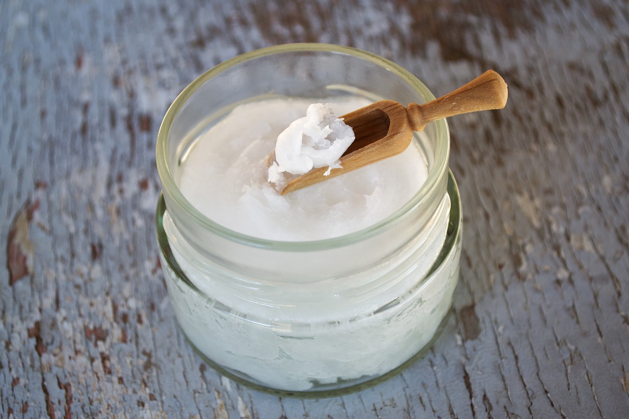 Fresh Coconut Oil in a Glass Jar with a Wooden Spoon